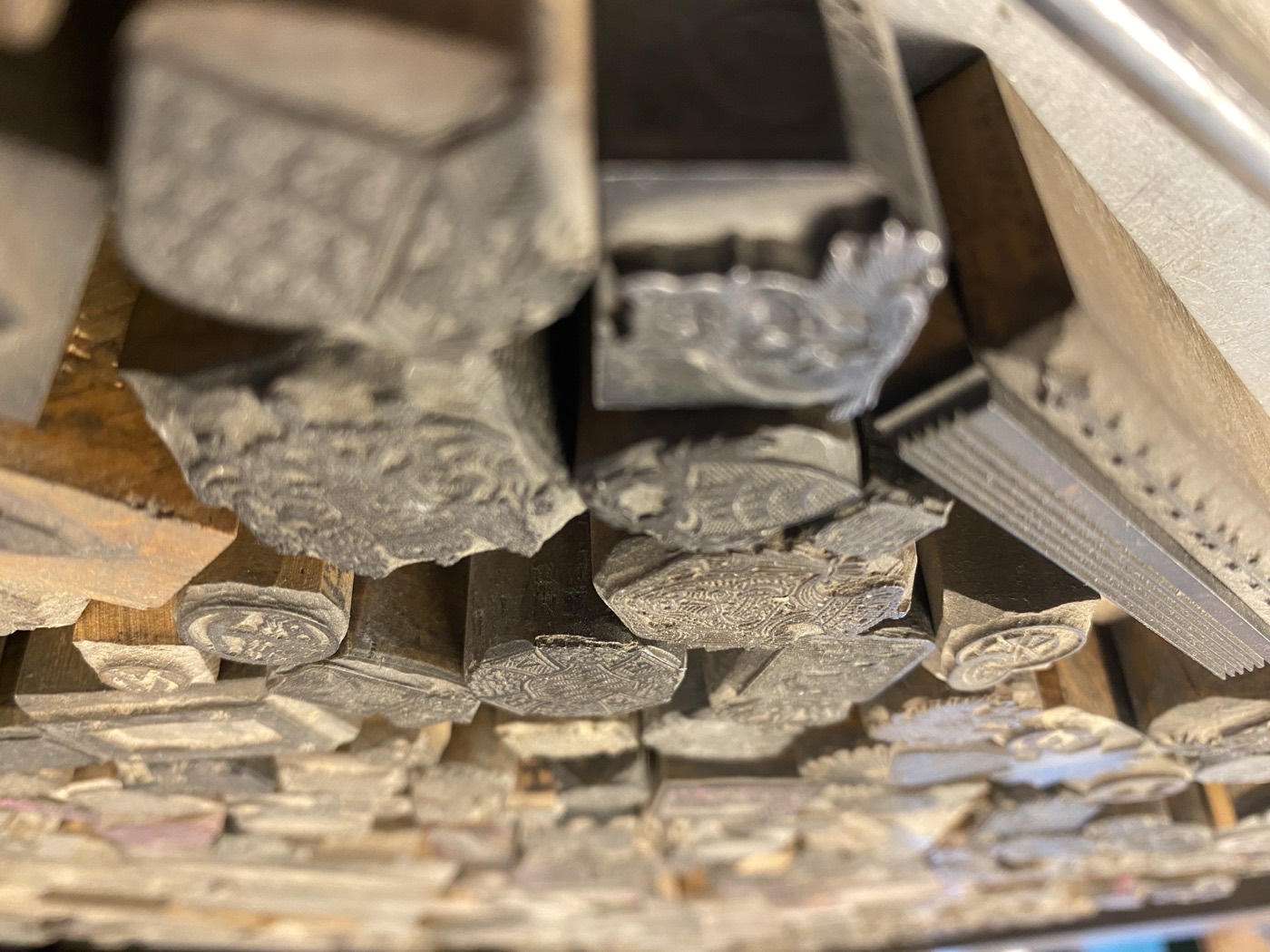 Clichés dicht an dicht im Kasten — Druckstöcke auf Holzfuß, viele mit Ornamenten und Vignetten