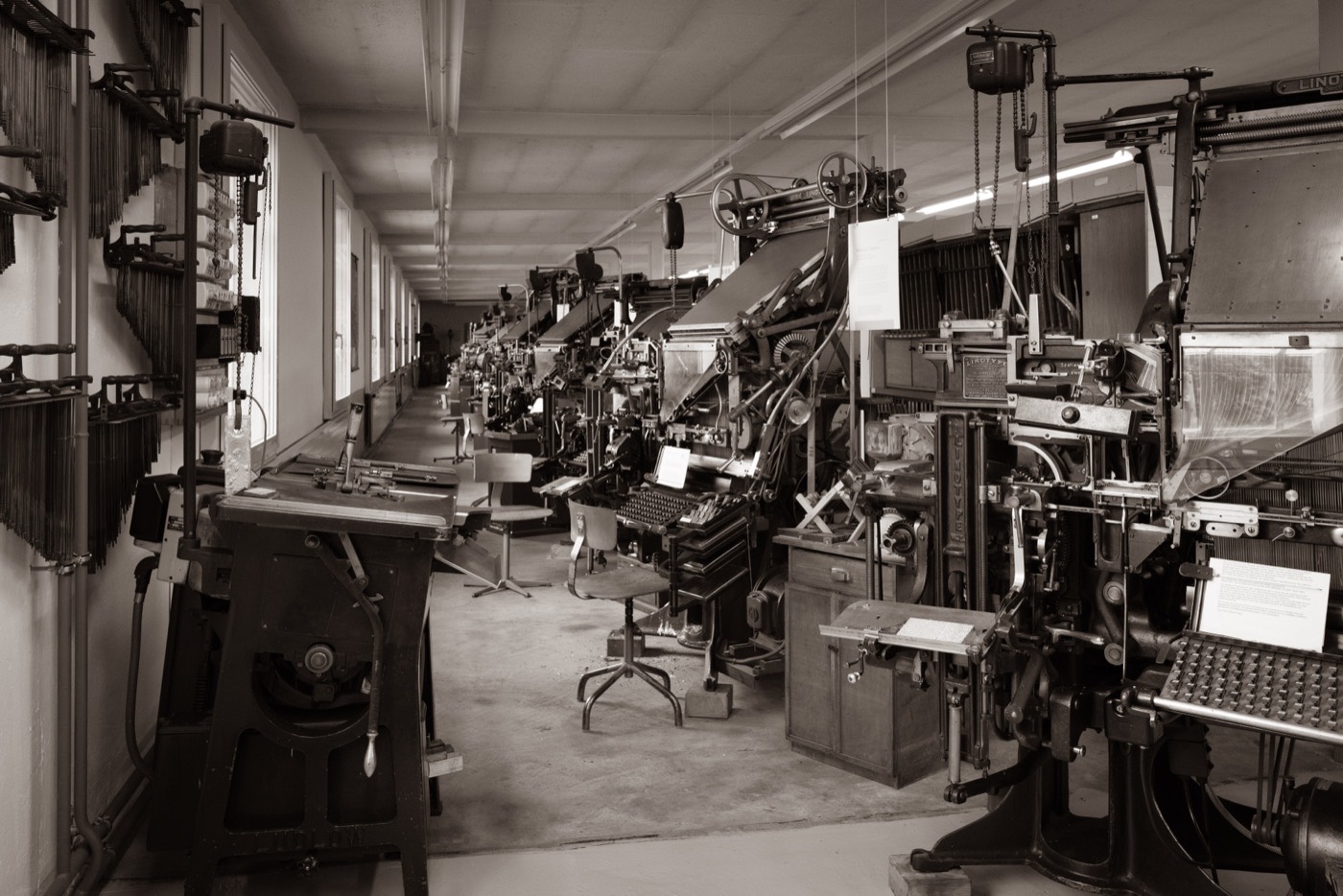 Der Setzmaschinensaal des Typorama: eine lange Reihe Linotype-Zeilensetzmaschinen, links die Ludlow und die Wand mit den Magazinen